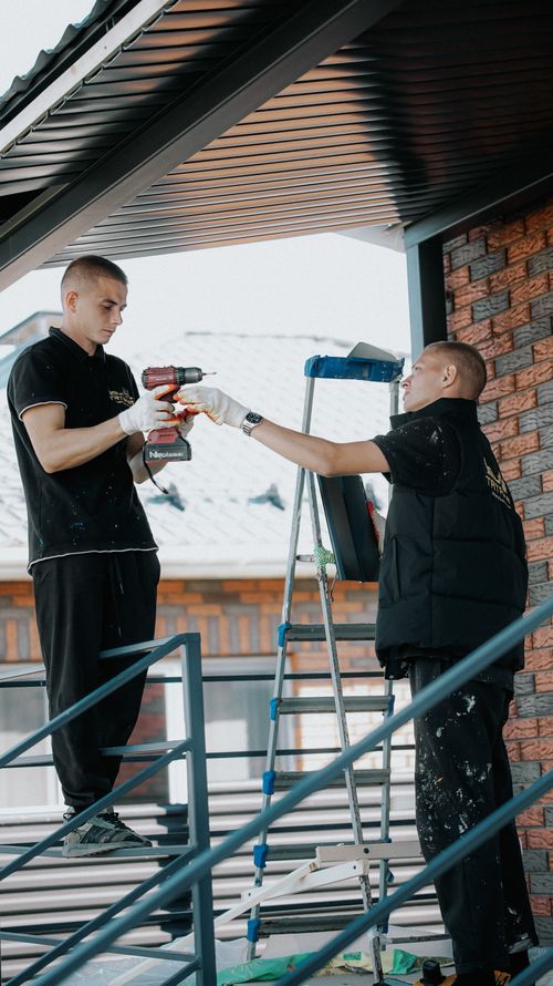 Free Two workers installing metal roofing on a residential building. Stock Photo