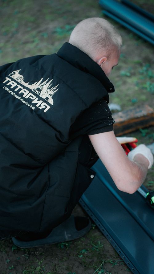 Free A worker in a black vest is assembling equipment outdoors with tools. Stock Photo