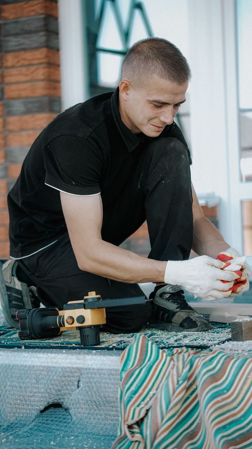 Free Young man using tools outdoors, focused on work, wearing gloves. Stock Photo