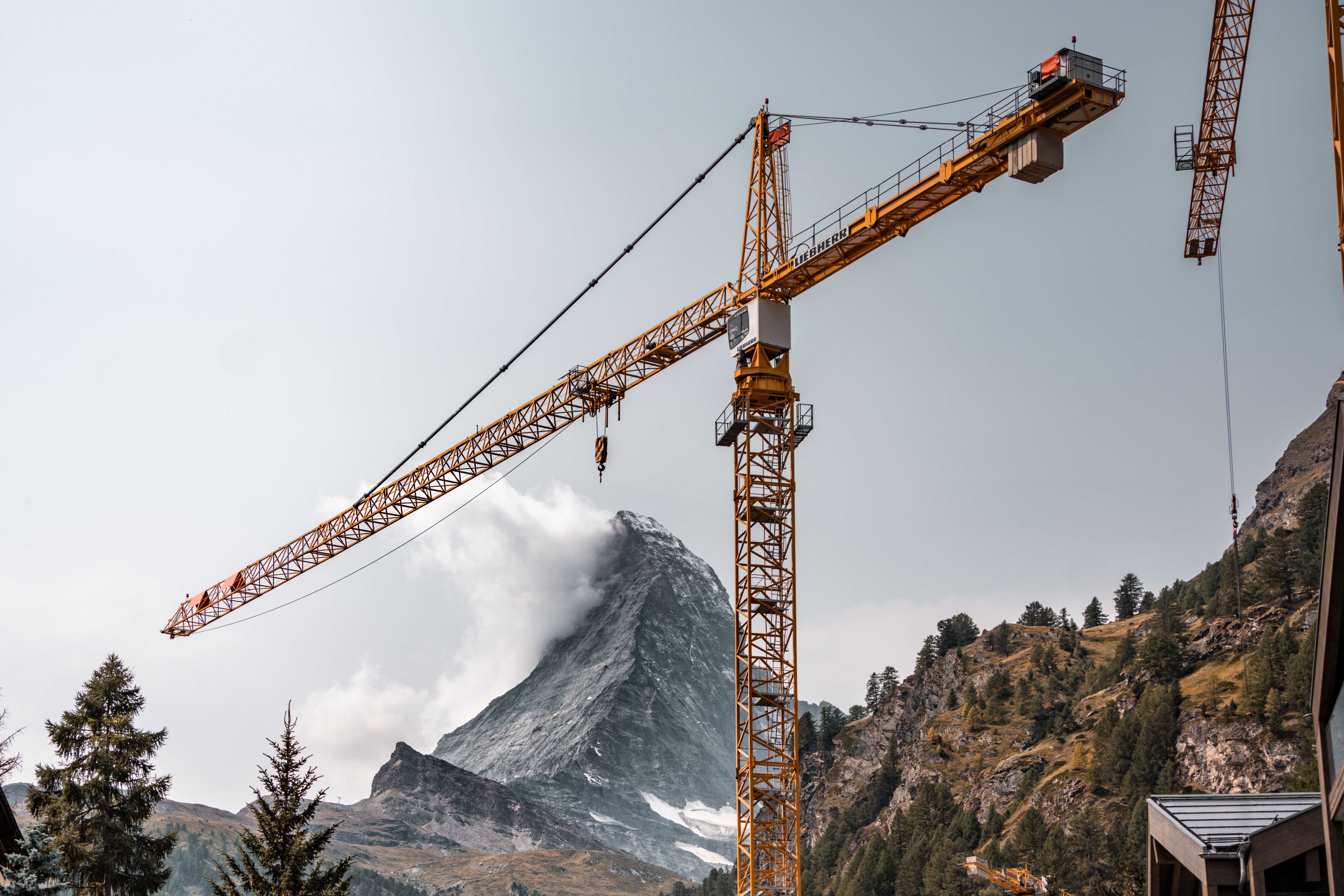 Tower cranes in Zermatt with a view of the iconic Matterhorn mountain, showcasing construction progress.