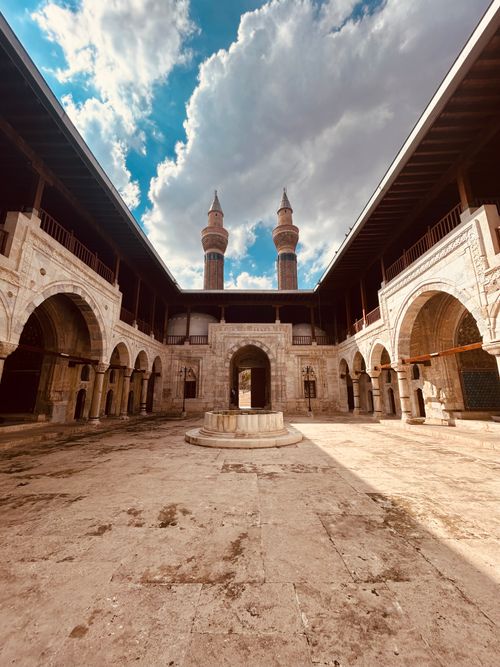 Free Beautiful historic mosque courtyard with ornate arches, minarets under a vibrant blue sky. Stock Photo