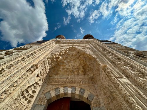 Free Detailed stone archway with intricate carvings under a vivid blue sky with clouds. Stock Photo