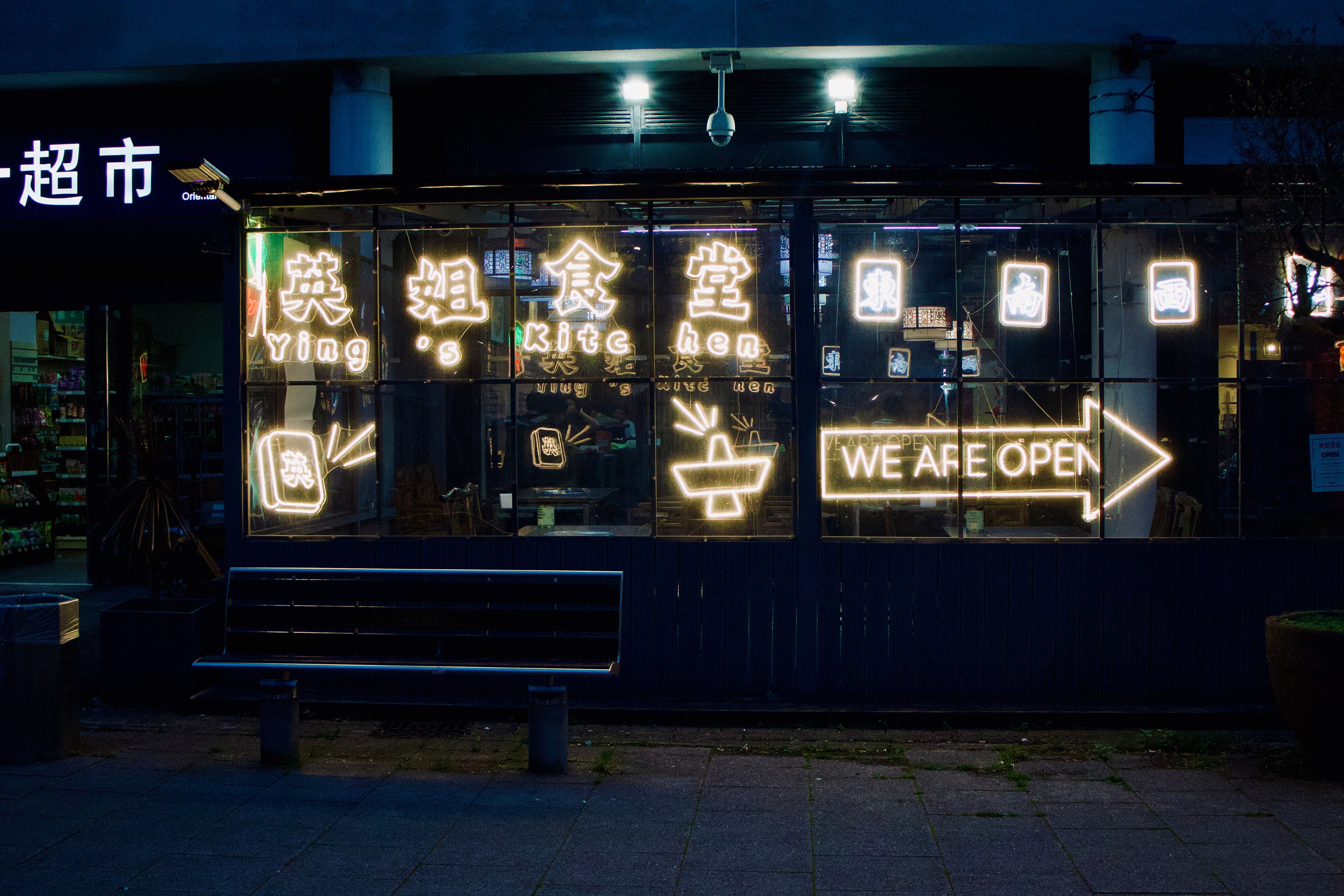 Vibrant neon signs illuminate the restaurant front in Coventry, showcasing an open invitation at night.