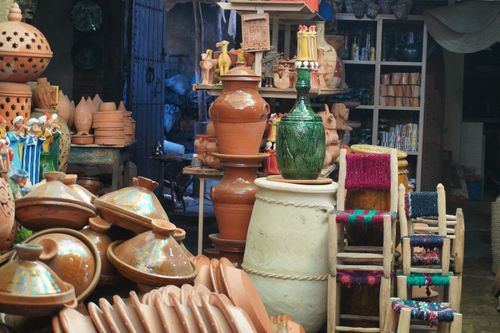 Free Vibrant display of handcrafted ceramics and woven chairs in a traditional market setting. Stock Photo