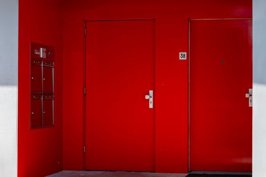 Striking red doors with mailboxes in a minimalist architectural setting.