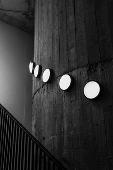 Black and white image of a concrete wall with circular lights in a modern industrial setting.