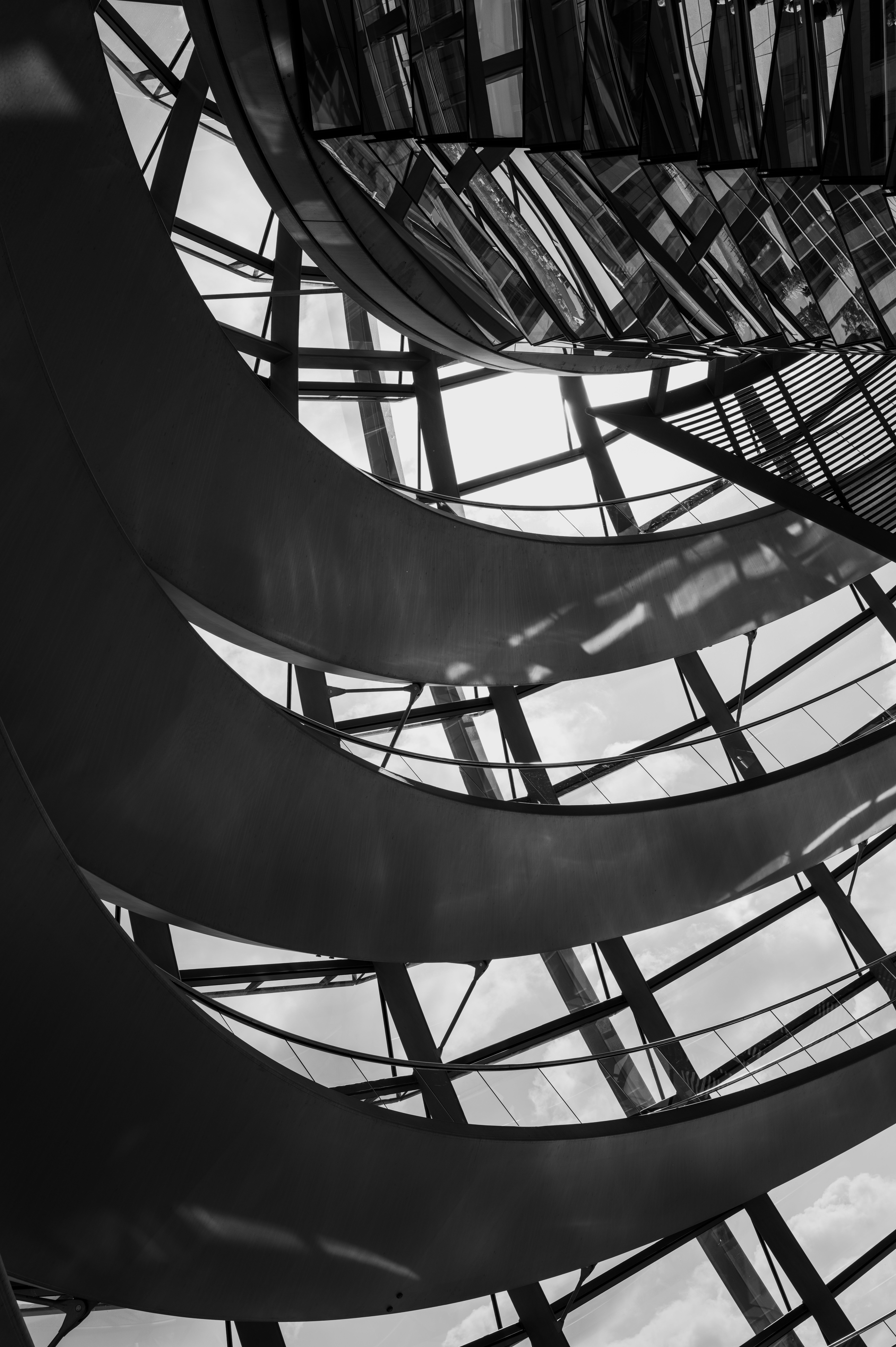 Black and white abstract view of modern architectural interior with curving lines and glass reflections.