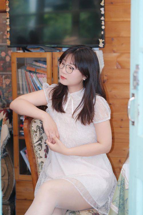 Free Young woman in a white dress sitting indoors, exuding a calm and relaxed mood. Stock Photo