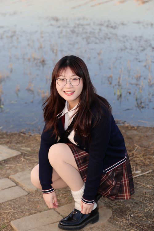 Free Smiling young woman in school uniform posing outdoors by a lake in Hefei, Anhui, China. Stock Photo