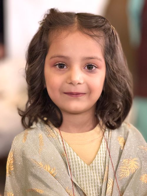 Free Charming portrait of a young girl with curled hair in traditional dress, smiling warmly. Stock Photo