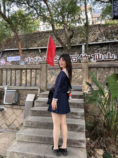 Free Young woman in navy dress posing on steps in Hefei, China with flag backdrop. Stock Photo