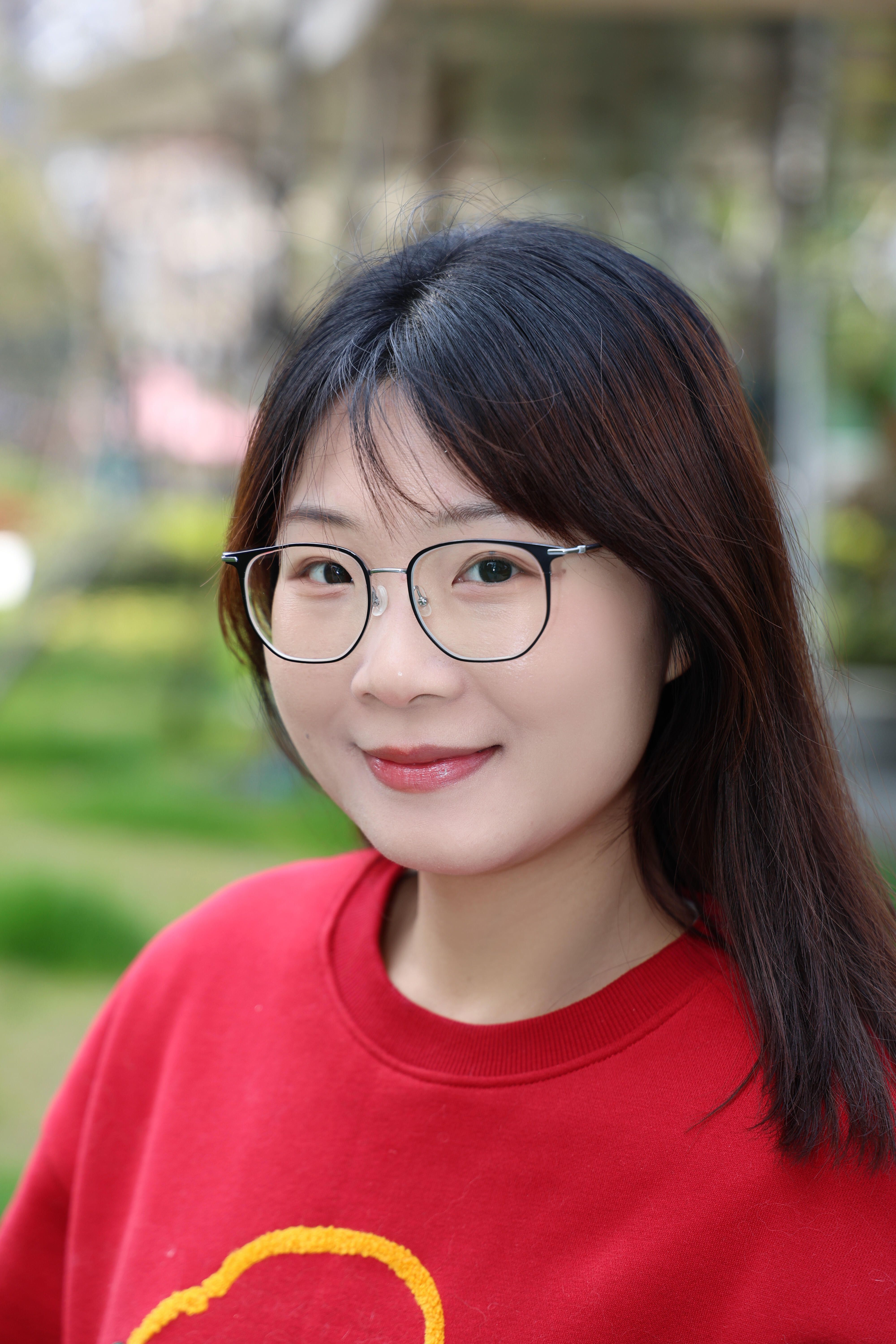 Beautiful portrait of an East Asian woman in a red sweater with glasses, outdoors in Hefei.
