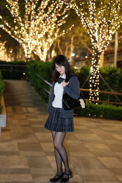 Free Young woman in a school uniform walking at night with festive lights in Hefei, China. Stock Photo
