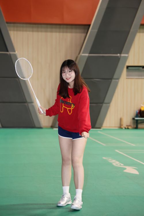 Free A young woman holding a badminton racket on an indoor court, ready to play. Stock Photo