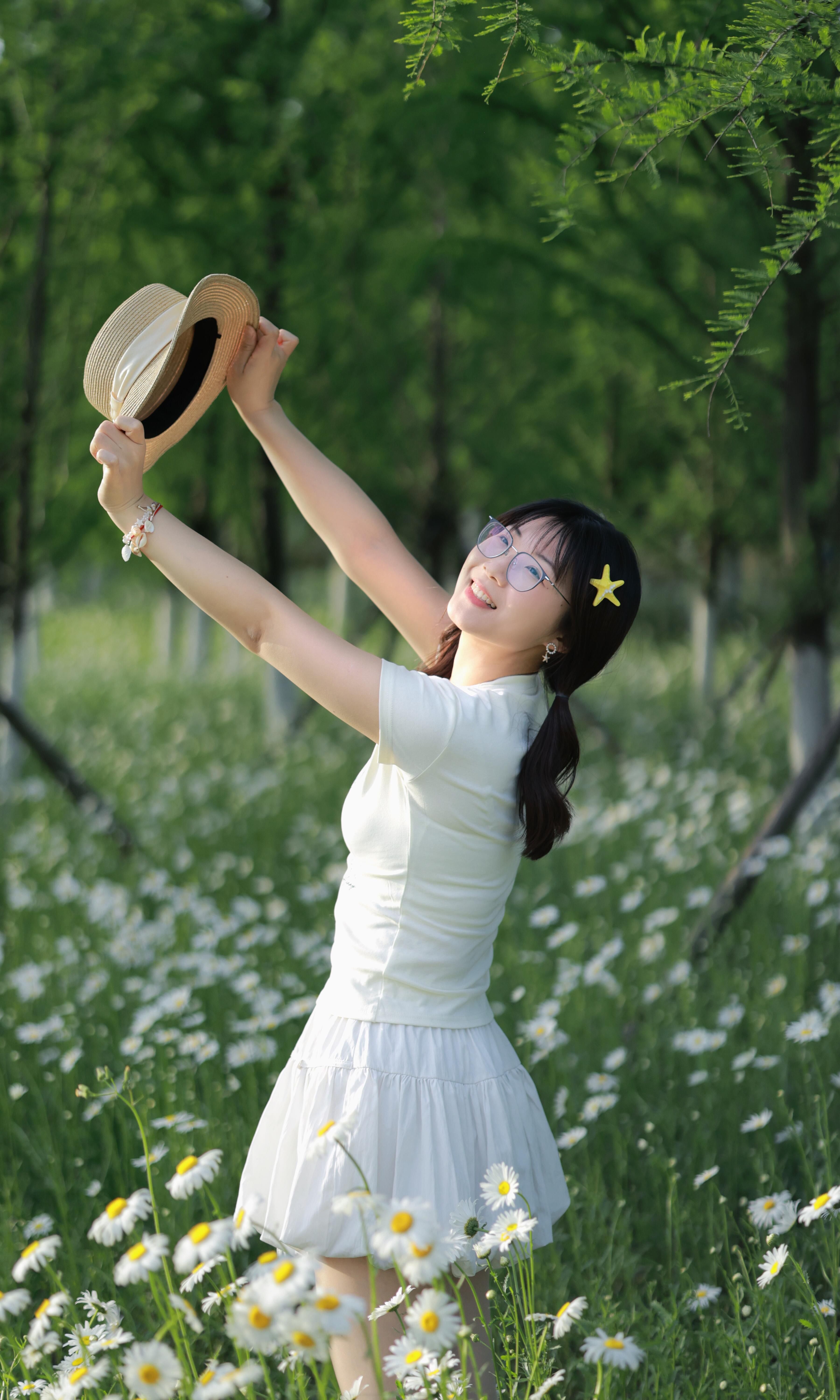 A cheerful woman enjoying a sunny day in a daisy-covered meadow in Hefei, China.