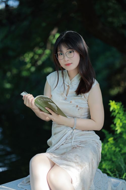 Free Young woman reading in a tranquil outdoor park setting in Hefei, China. Stock Photo