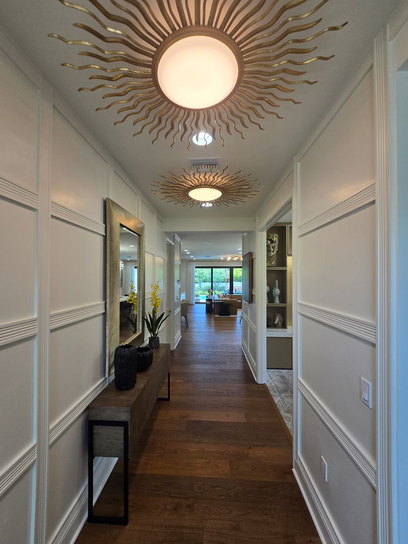 Narrow hallway with wood flooring, modern decor and lighting fixtures showing how small corridors can look styled