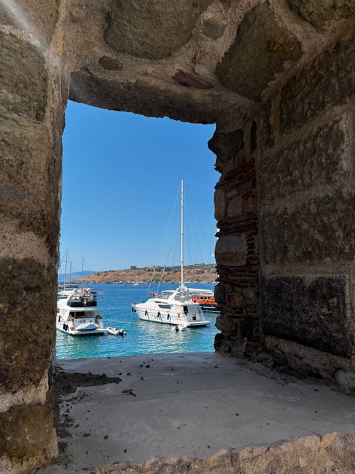 Free View of yachts in Bodrum Marina through an ancient stone window on a sunny day. Stock Photo