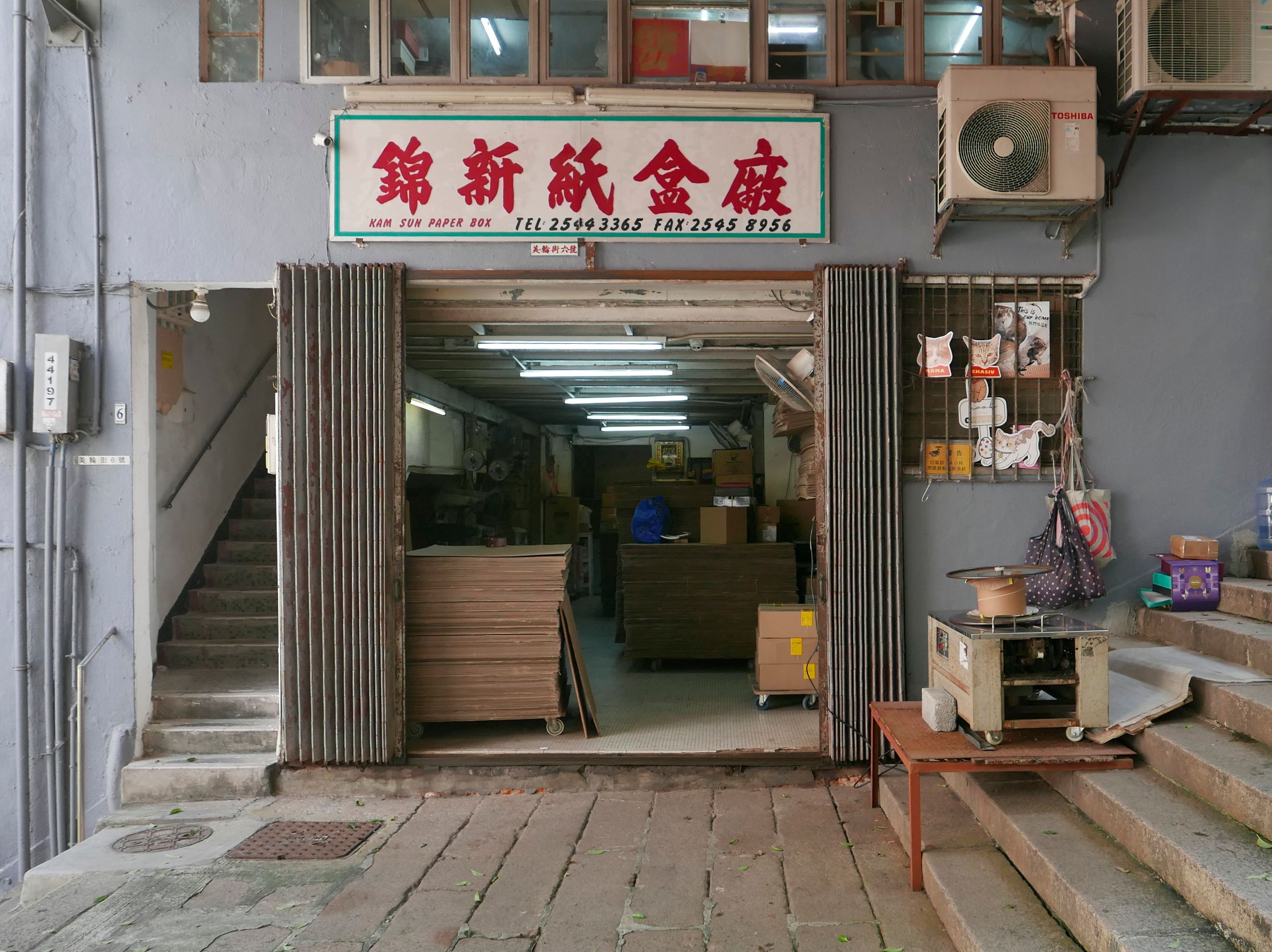 The open front of an old workshop under a red and white Chinese sign, with steps leading up to it