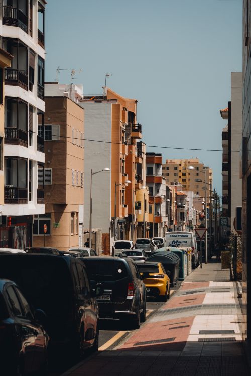 Free A vibrant urban street scene in San Sebastián de La Gomera, featuring colorful apartments and parked cars. Stock Photo
