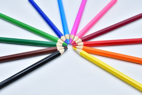 Free A colorful arrangement of colored pencils fanned out on a white surface. Stock Photo
