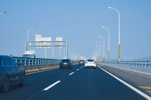 Free Vehicles traveling on a modern bridge spanning across the ocean, offering scenic coastal views. Stock Photo