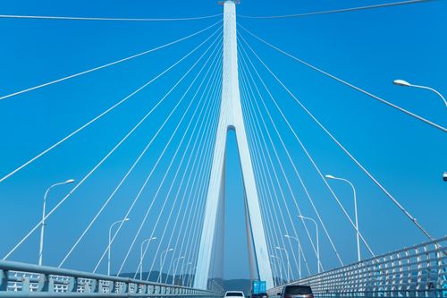 Free Impressive modern suspension bridge with traffic under a clear blue sky in a coastal city. Stock Photo