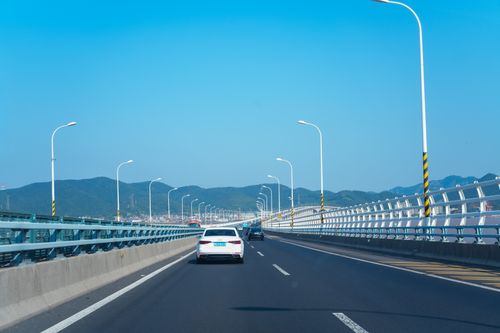 Free View of vehicles driving on Zhoushan Bridge, Zhejiang, under a clear blue sky. Stock Photo