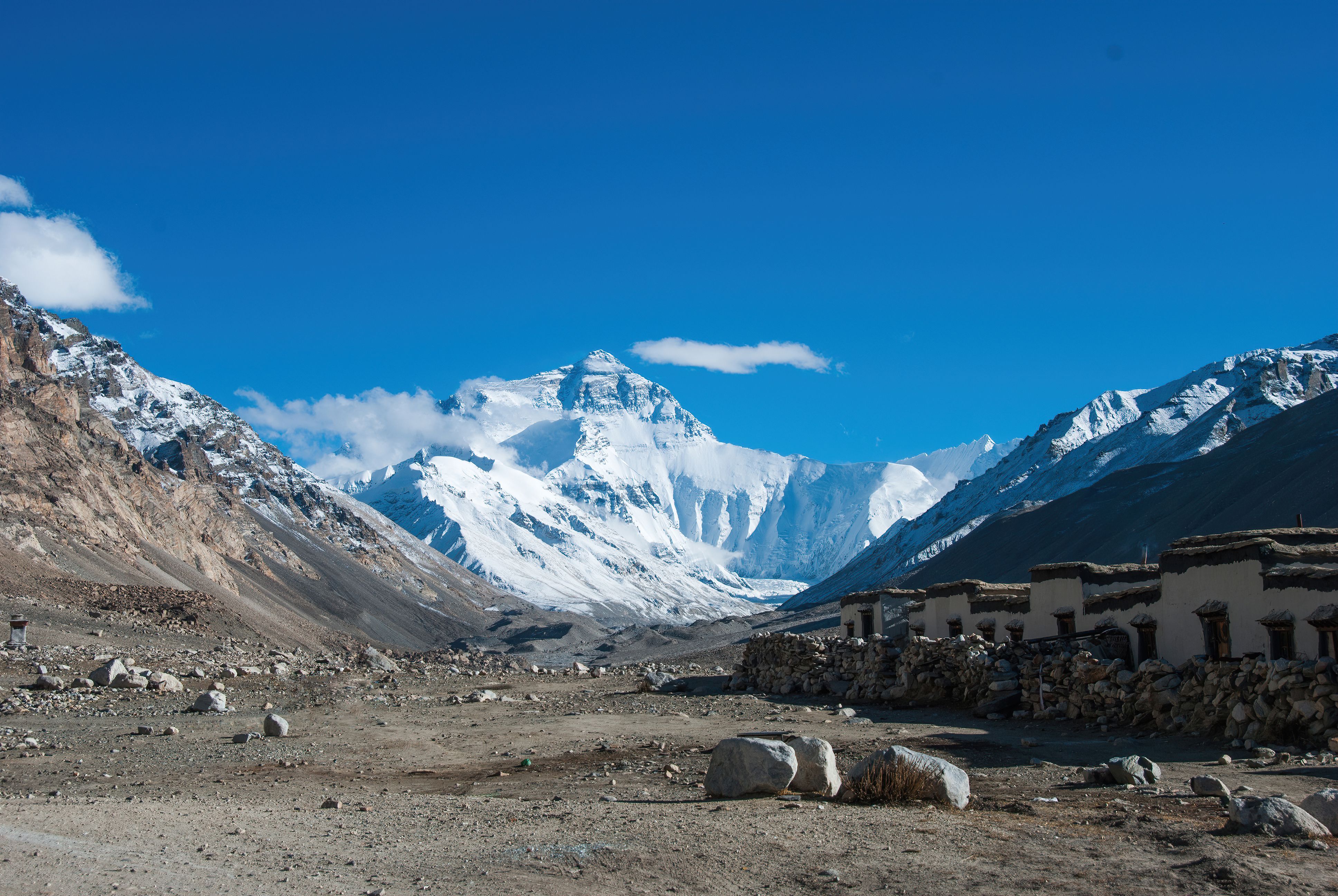 Stunning view of Mount Everest with clear blue skies, captured from Tibet's rugged terrain.