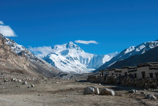 Stunning view of Mount Everest with clear blue skies, captured from Tibet's rugged terrain.