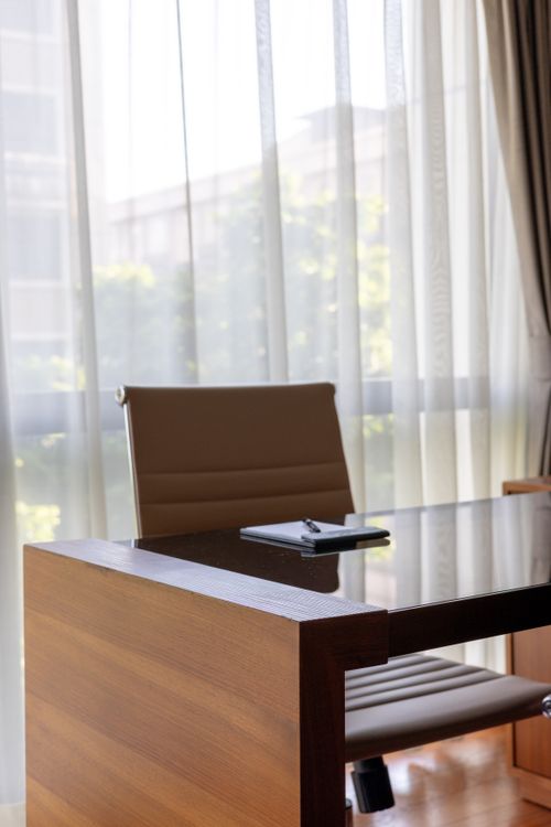 Free Elegant office chair and desk by large sunlit window, ideal for corporate settings. Stock Photo