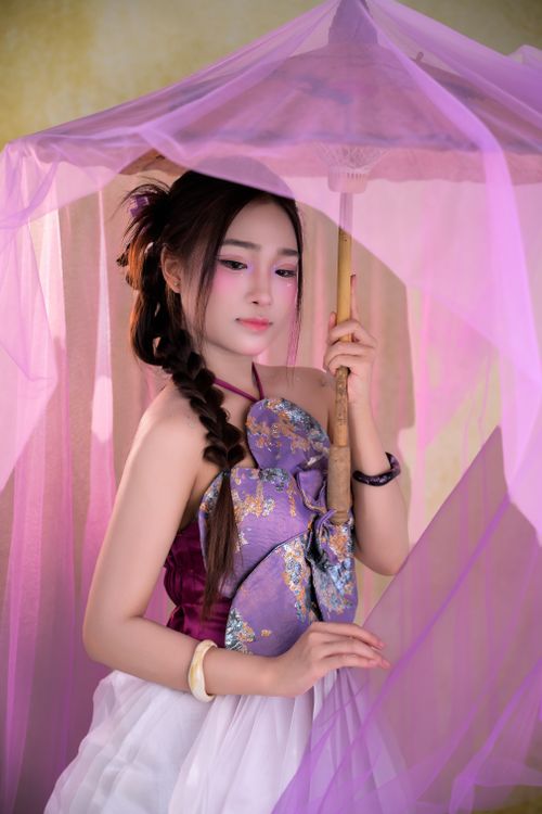 Free Elegant Asian woman holding a traditional purple parasol, dressed in cultural attire. Stock Photo