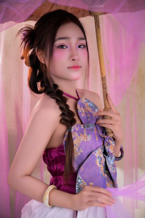 Free Elegant portrait of a woman holding a traditional parasol in vibrant colors and attire. Stock Photo