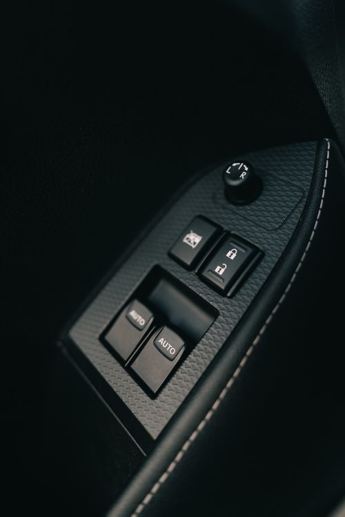 Free Detailed view of a car door control panel featuring window and lock buttons in a sleek automotive interior. Stock Photo