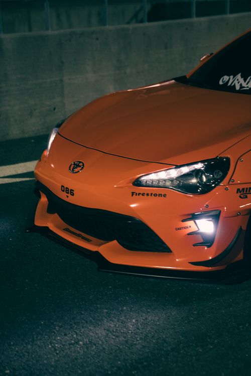 Free Close-up of an orange sports car with custom decals captured at night. Stock Photo