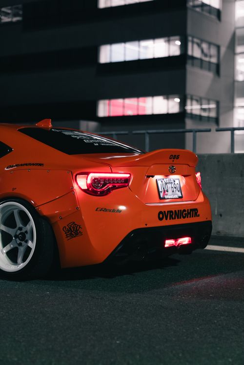 Free Vibrant orange sports car parked at night in an urban area, showcasing a stylish design. Stock Photo