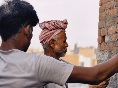 Free Two construction workers focusing on building a brick wall under natural light outdoors. Stock Photo
