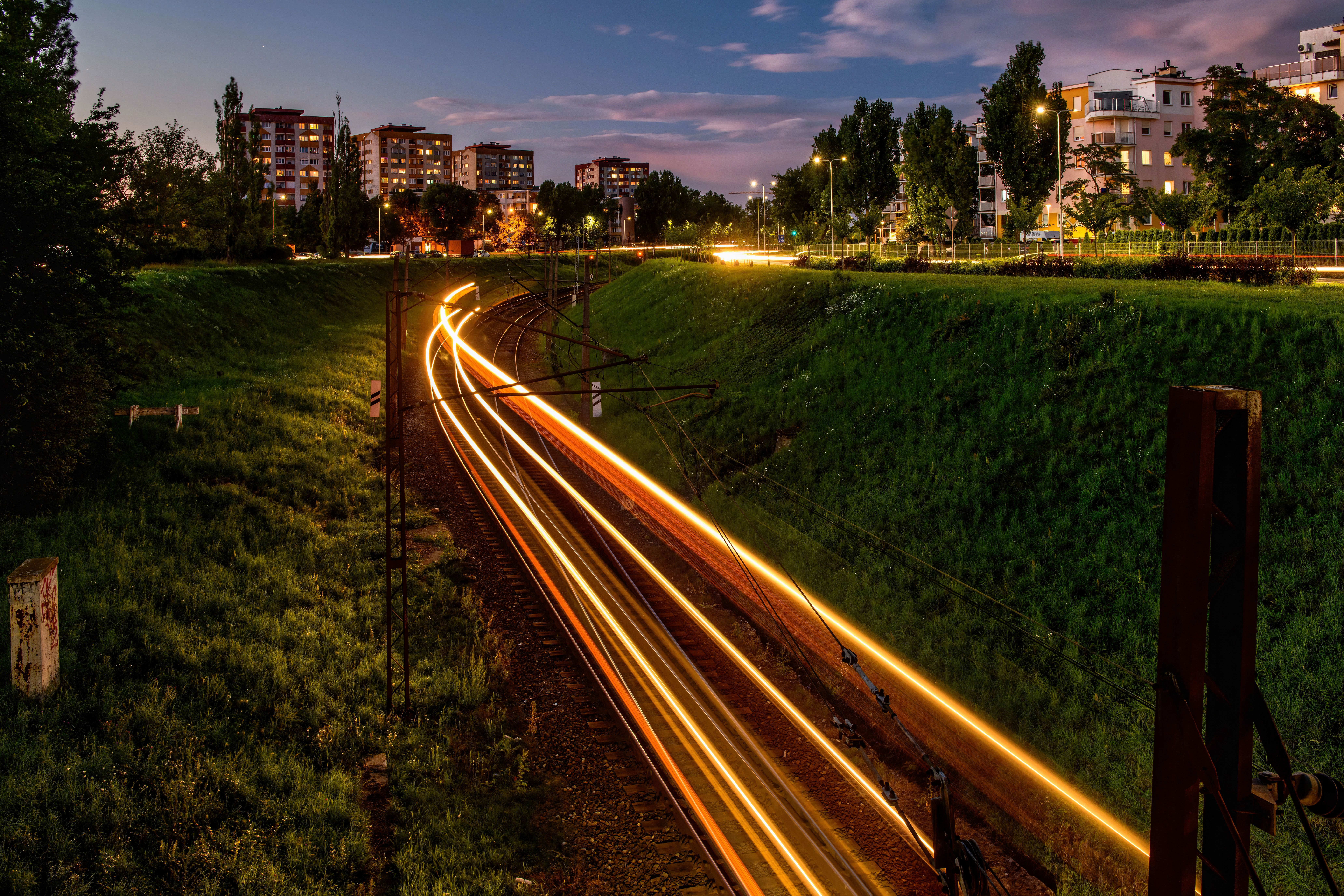 Long exposure of train tracks with light trails in Toruń, Poland, during the evening.