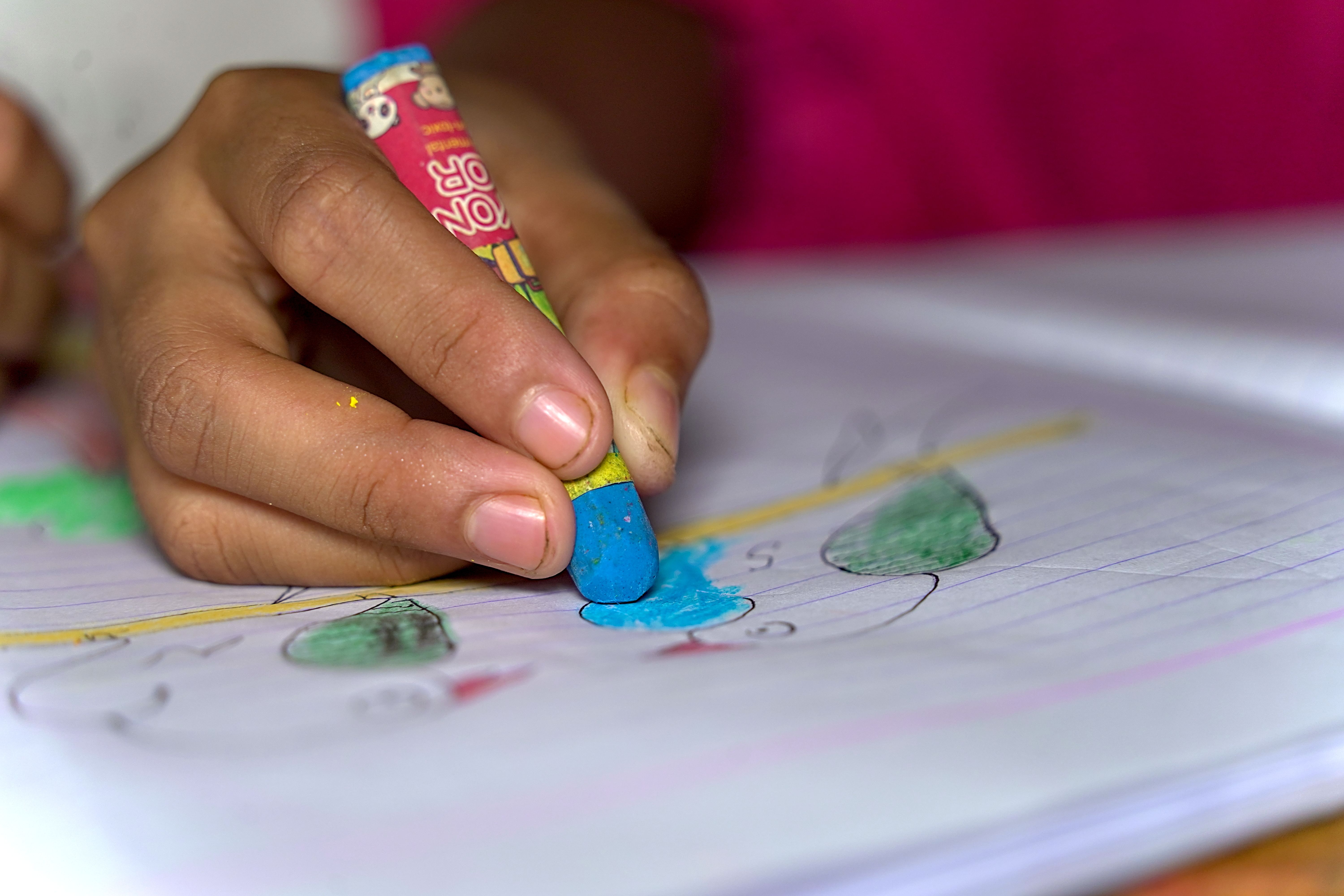 クレヨンで色をぬる子どもの手元
