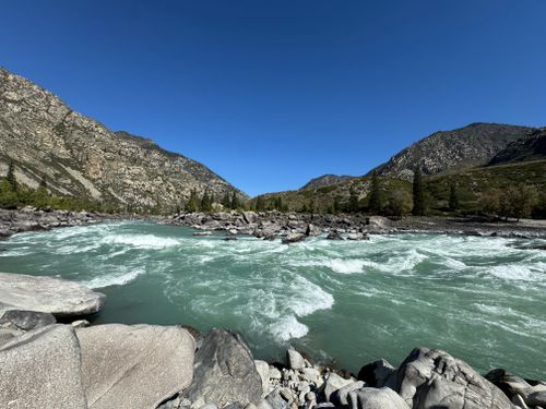 Free Discover the breathtaking beauty of a turquoise river cutting through majestic mountains under a clear blue sky. Stock Photo