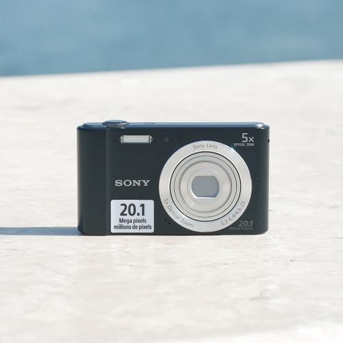 Free Black compact digital camera with lens extended, outdoors on marble surface. Stock Photo