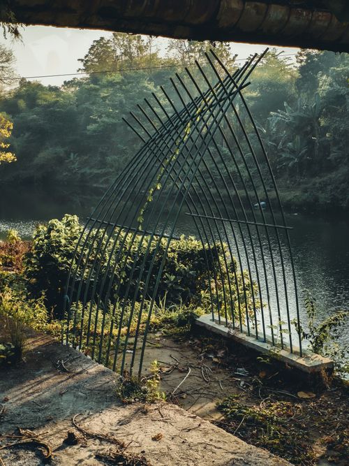 Free Artistic metal structure by a tranquil lakeside, surrounded by lush greenery. Stock Photo