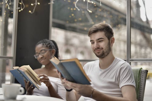 Happy diverse friends reading books in modern cafeteria