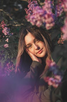 在一个阳光明媚的日子里，一位年轻女子置身于宁静的花园，四周盛开着紫丁香