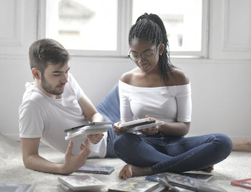 Couple Sitting on the Floor Choosing What Movie to Watch