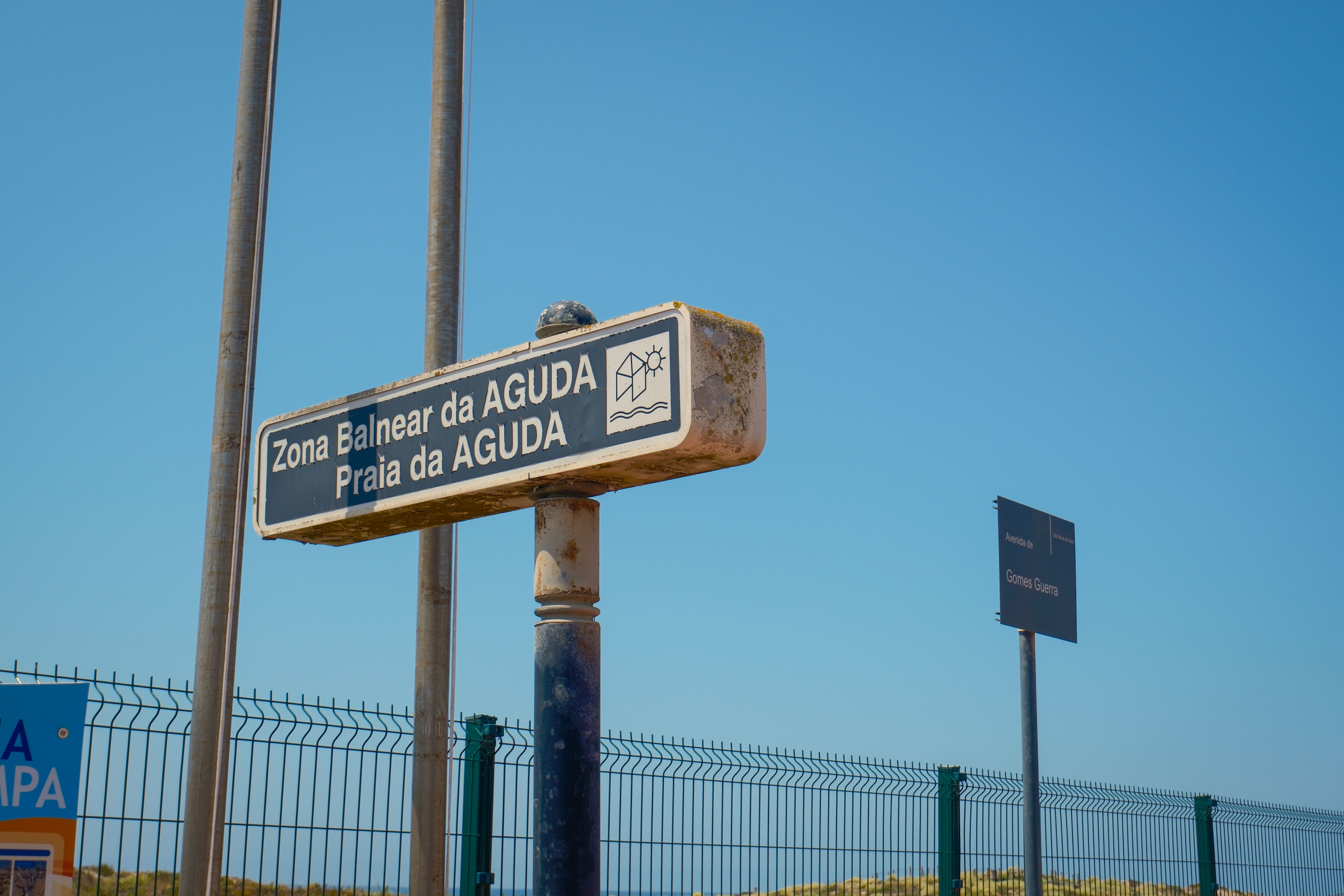 View of Zona Balnear da Aguda sign under clear blue sky in Porto, Portugal.