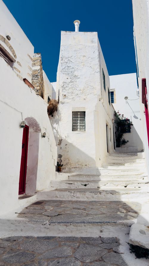 Free Explore a picturesque narrow alleyway with white architecture on a sunny day in Greece. Stock Photo