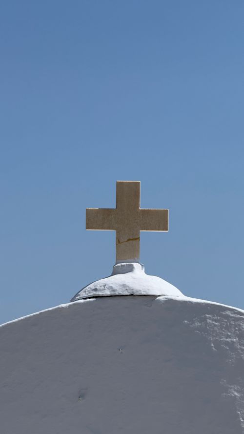 Free A whitewashed church cross set against a clear blue sky in Santorini, Greece. Stock Photo