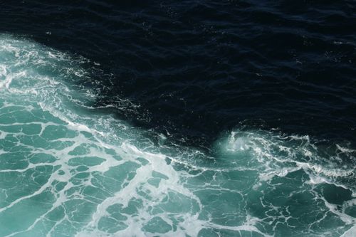 Free A stunning aerial view of ocean waves with contrasting aqua and dark blue tones. Stock Photo