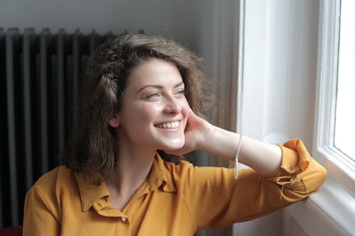 Free Happy young woman looking out window at home Stock Photo